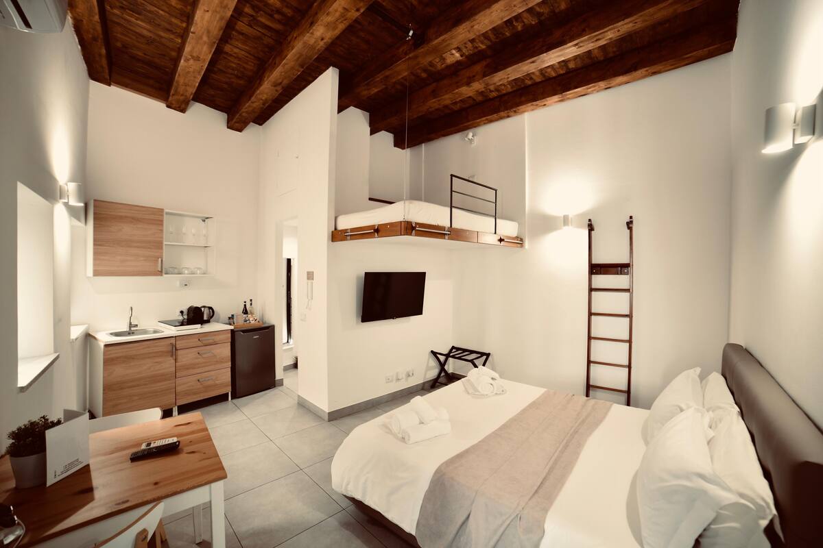 Un dormitorio moderno con una litera, un escritorio, un televisor de pantalla plana y techo de madera.