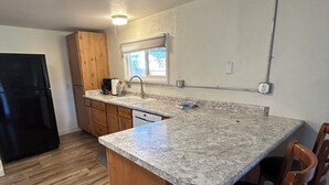 Eine Küche mit Holzschränken, einer Granitarbeitsplatte, einem eingebauten Geschirrspüler und einem Fenster über der Spüle.