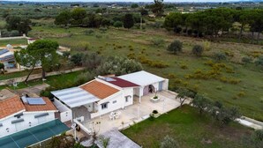 Une maison avec un toit en tuiles, une terrasse dotée de mobilier d’extérieur et une vue sur un paysage verdoyant.