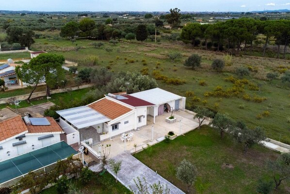 Une maison avec un toit en tuiles, une terrasse dotée de mobilier d’extérieur et une vue sur un paysage verdoyant.