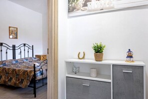 Une chambre à coucher comprenant un lit, une table de chevet, une étagère avec des objets décoratifs et un mur orné d’une inscription.