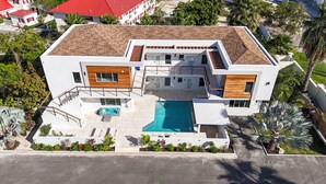 Ein modernes, zweistöckiges Haus mit Swimmingpool, überdachter Terrasse und einer Treppe, die zu einem Balkon führt.