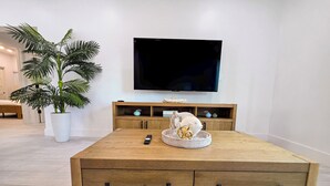 Ein modernes Wohnzimmer mit einem Couchtisch aus Holz, einem an der Wand montierten Fernseher und einem Topfpflanzen.