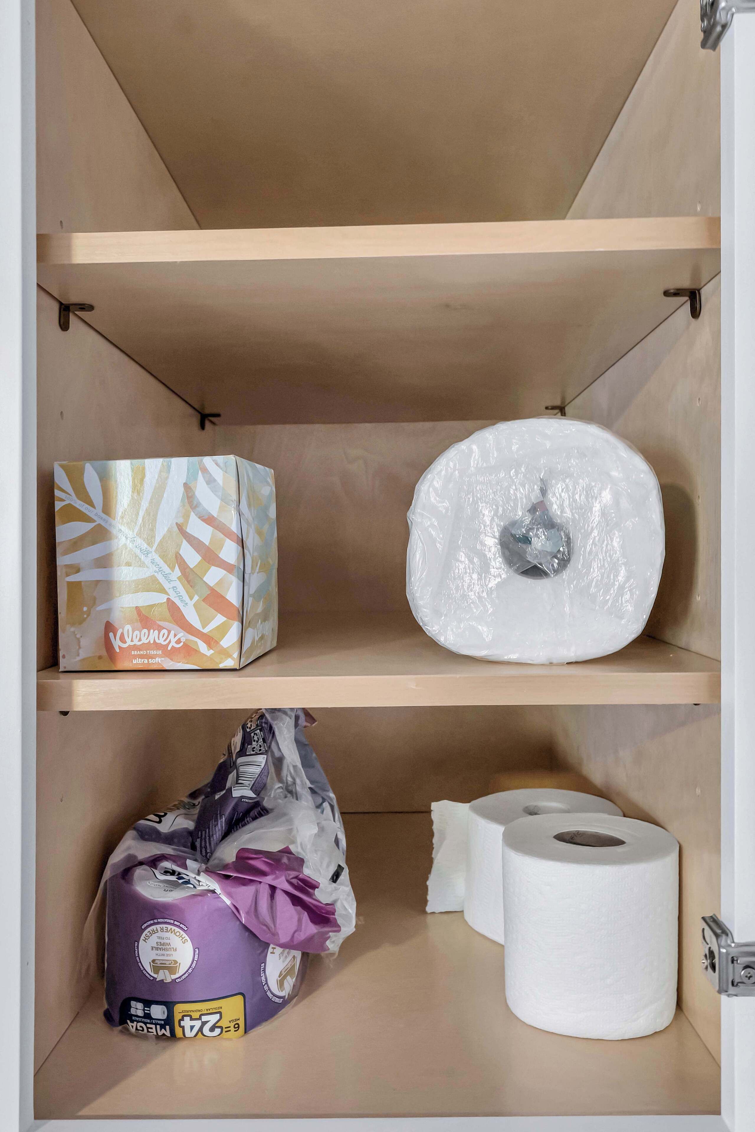 Une étagère avec une boîte de mouchoirs Kleenex, un rouleau de papier toilette et un paquet d’essuie-tout.