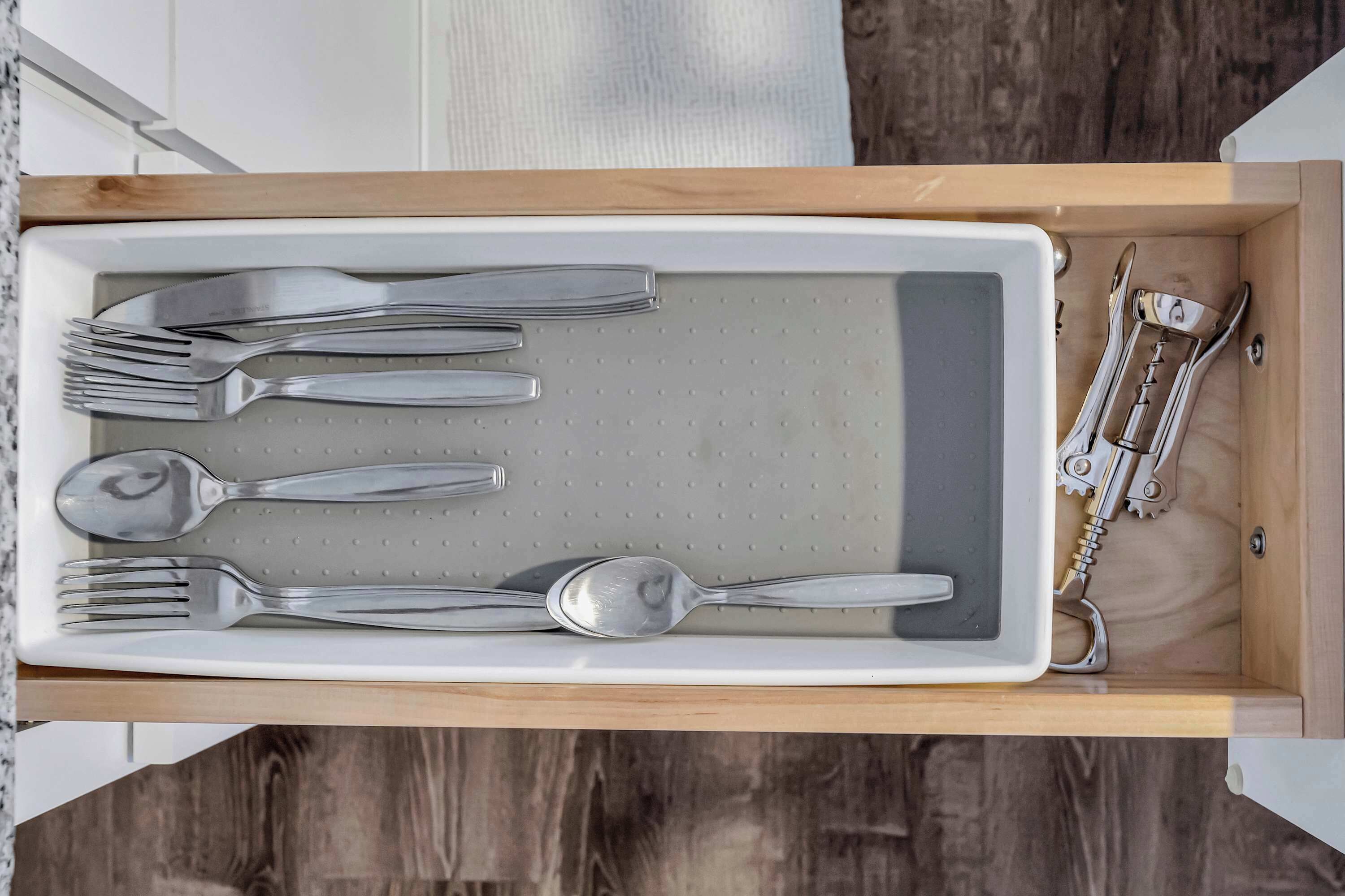 A drawer containing a set of silverware including forks, spoons, and a knife.