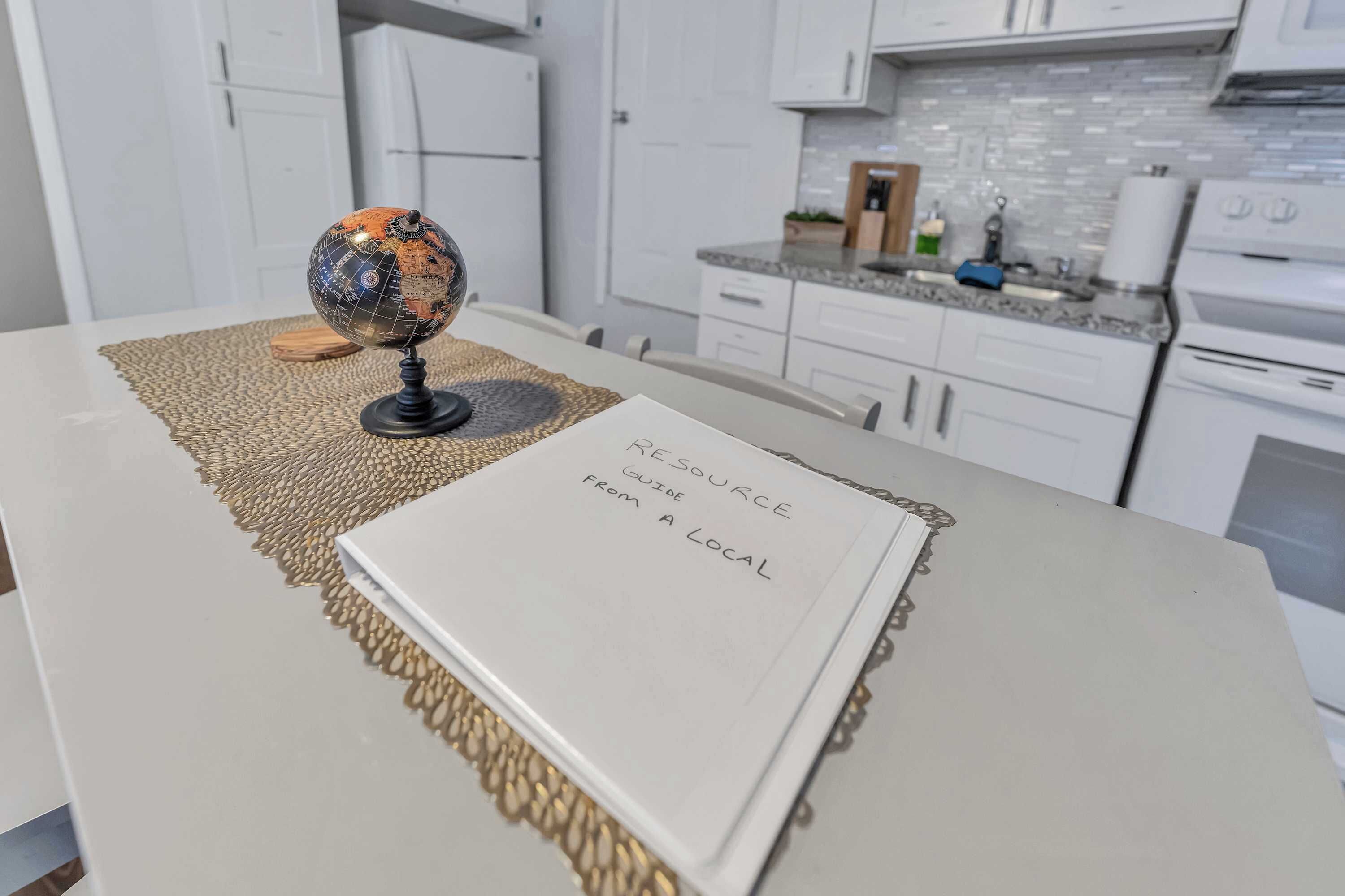 A kitchen with white cabinets, a countertop with kitchen appliances, and a globe on a table.