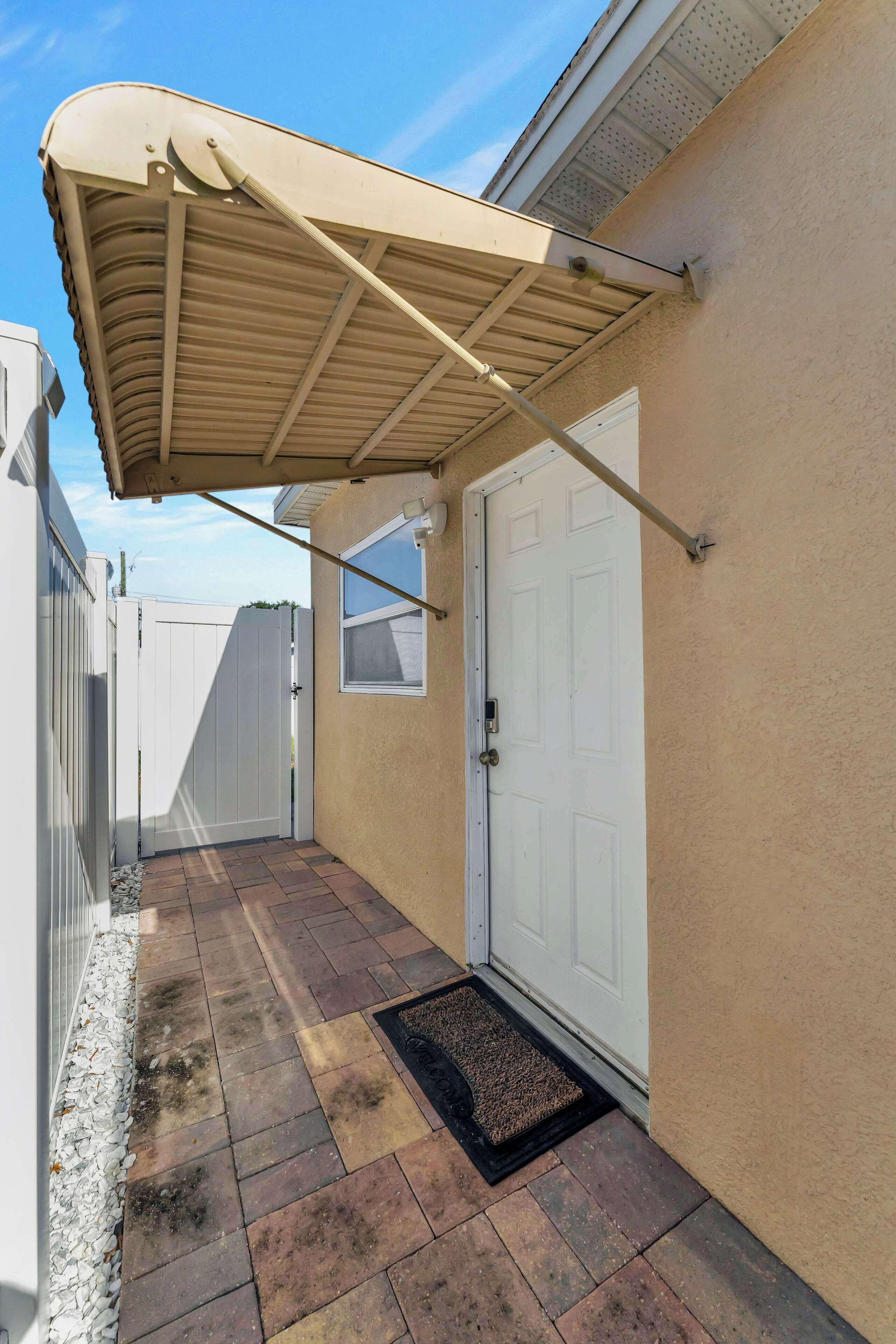 Un patio cubierto con una puerta blanca y un ventanal pequeño.