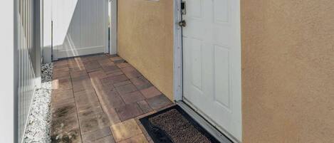 Un patio cubierto con una puerta blanca y un ventanal pequeño.