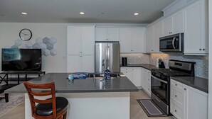 A modern kitchen with white cabinets, stainless steel appliances, and a central island.
