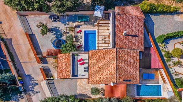 An aerial view of a resort with multiple swimming pools, sun loungers, and a covered patio area.