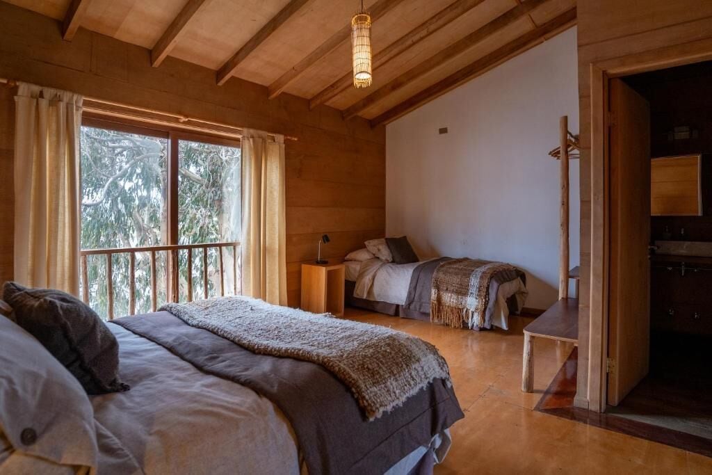 Una habitación de madera con una cama, una mesita de noche y un banco.