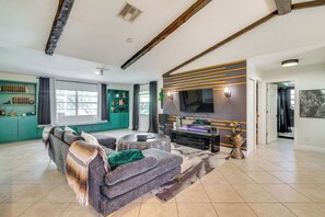Ein modernes Wohnzimmer mit einem Ecksofa, einem Flachbildfernseher und einer dekorativen Wandverkleidung.