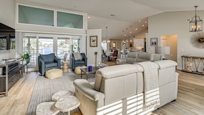 A spacious living area with a high ceiling, large windows, and a modern kitchen in the background. - 2 Mi to South Beach: Waterfront Home w/ Lanai! (Marco Island)