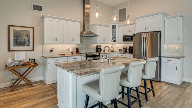 A modern kitchen with white cabinetry, a central island with bar stools, stainless steel appliances, and pendant lighting. - 2 Mi to South Beach: Waterfront Home w/ Lanai! (Marco Island)