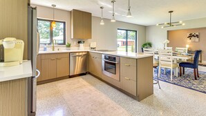 Eine moderne Küche mit Edelstahlgeräten, Holzschränken und Pendelleuchten.