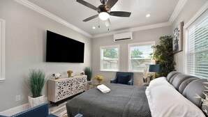 A bedroom with a bed, a ceiling fan, a TV, a dresser, and a window with blinds. - Walk to UC Davis Medical Center! Duplex w/ Patio (Sacramento)