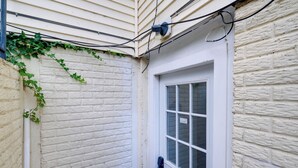 A white door with a window, a white brick wall, and a white siding exterior. - 2 Mi to Umd: Apt w/ Free Parking in Silver Spring! (Silver Spring)