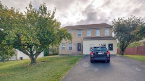 Une maison à deux étages avec un garage, une allée et un arbre dans le jardin.