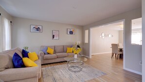 Un salon moderne avec un canapé beige, une table basse en verre et un tapis à motifs.