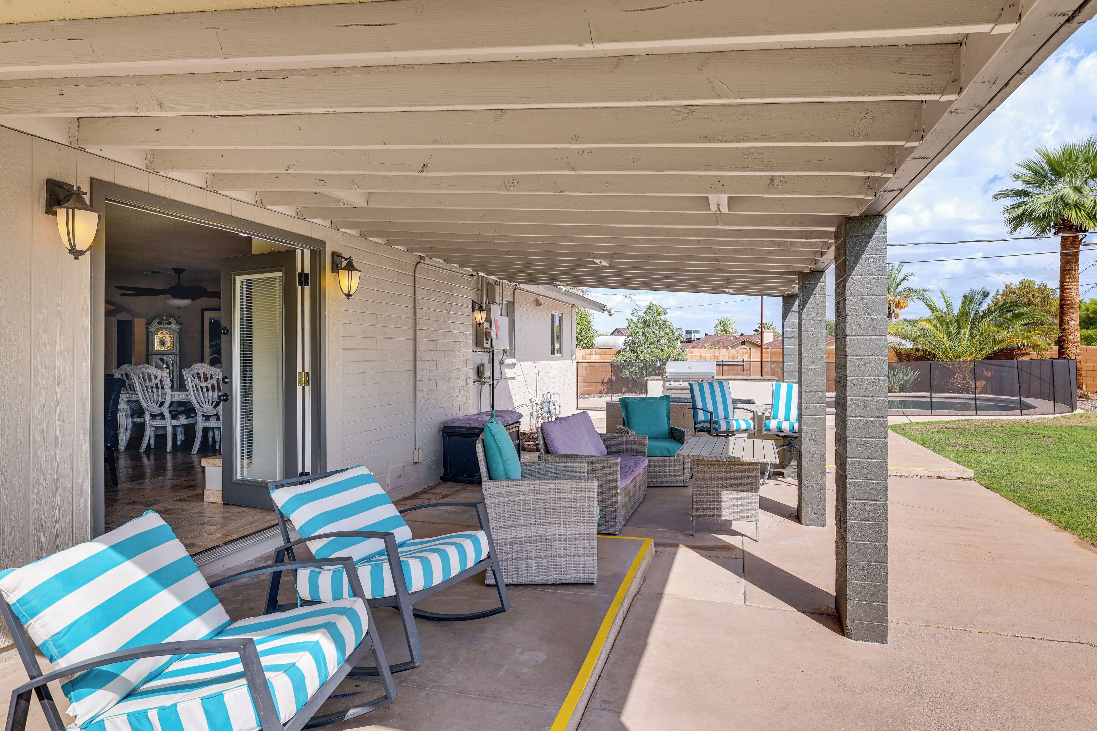 An outdoor patio with wicker furniture, a covered area, and a view of the backyard.