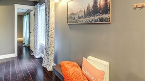 A hallway with a wooden bench, a framed picture of a forest, and a wall-mounted light fixture. - Commuter-friendly Vancouver Rental w/ Yard (Vancouver)