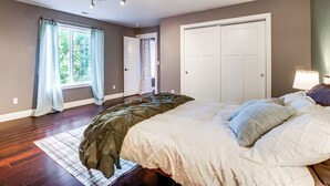 A bedroom with a large bed, a window with curtains, a door, and a chandelier. - Commuter-friendly Vancouver Rental w/ Yard (Vancouver)