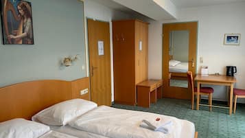 Ein Hotelzimmer mit zwei Betten, einem Schreibtisch, einem Stuhl, einem Kleiderschrank und einem Bild an der Wand.