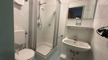 Un baño con ducha acristalada, inodoro y lavamanos con espejo.