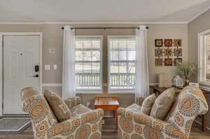 Un salón con dos sillones estampados, una mesita de madera y un tablero de ajedrez.