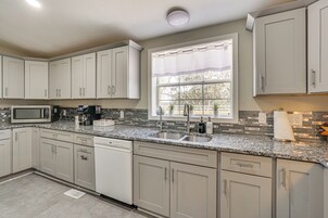 A kitchen with white cabinets, a stainless steel sink, and a microwave.
