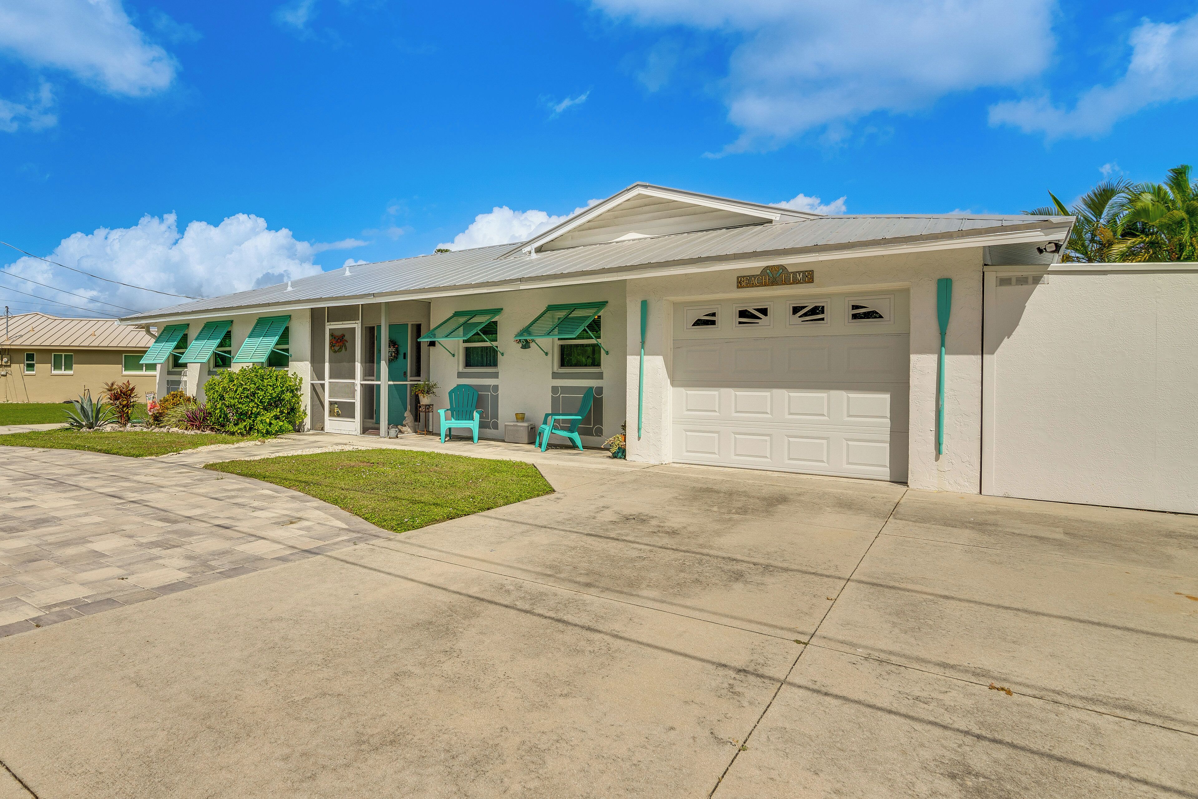A two-story house with a garage, a covered porch with chairs, and a well-maintained lawn.