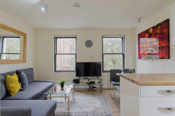 A modern living room with a sofa, coffee table, TV, and a glass cabinet.