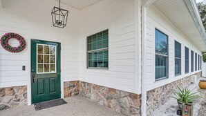 A house with a green door, stone foundation, and a stone wall.