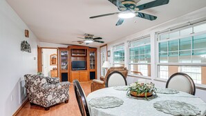 A dining area with a round table, chairs, and a ceiling fan.