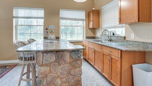 A kitchen with a stone island, wooden cabinets, and a large window.