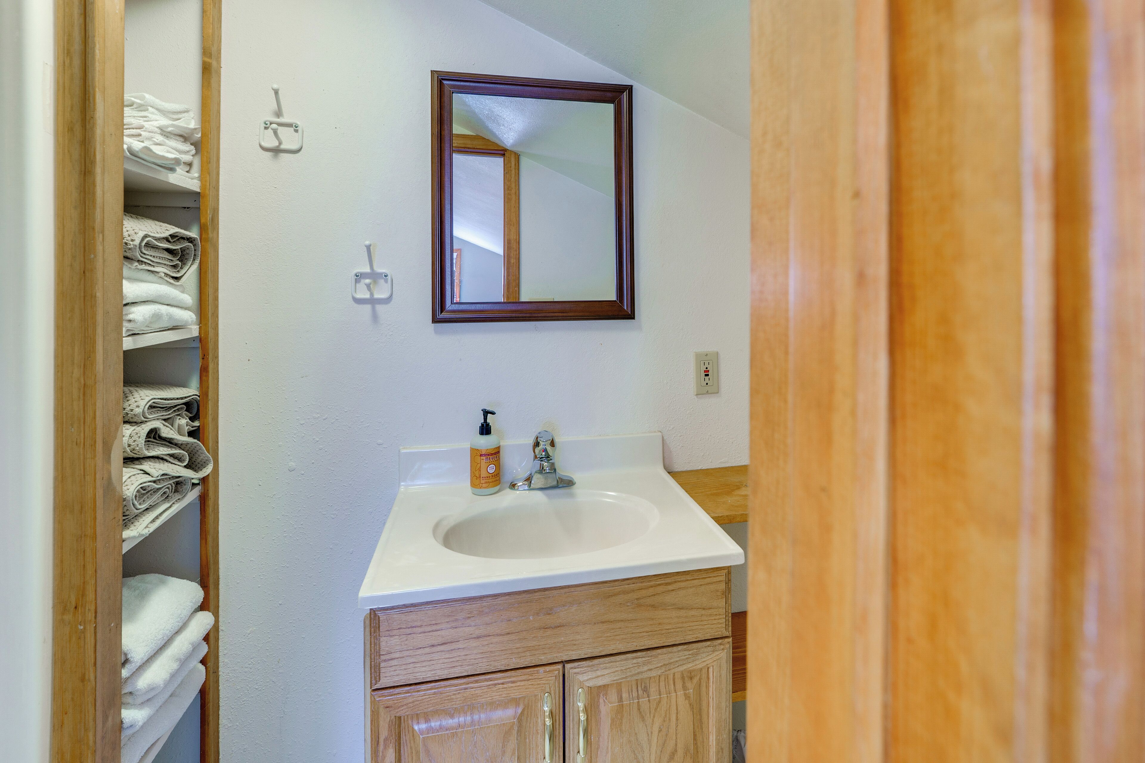 A bathroom with a white sink, wooden cabinets, and a mirror on the wall.
