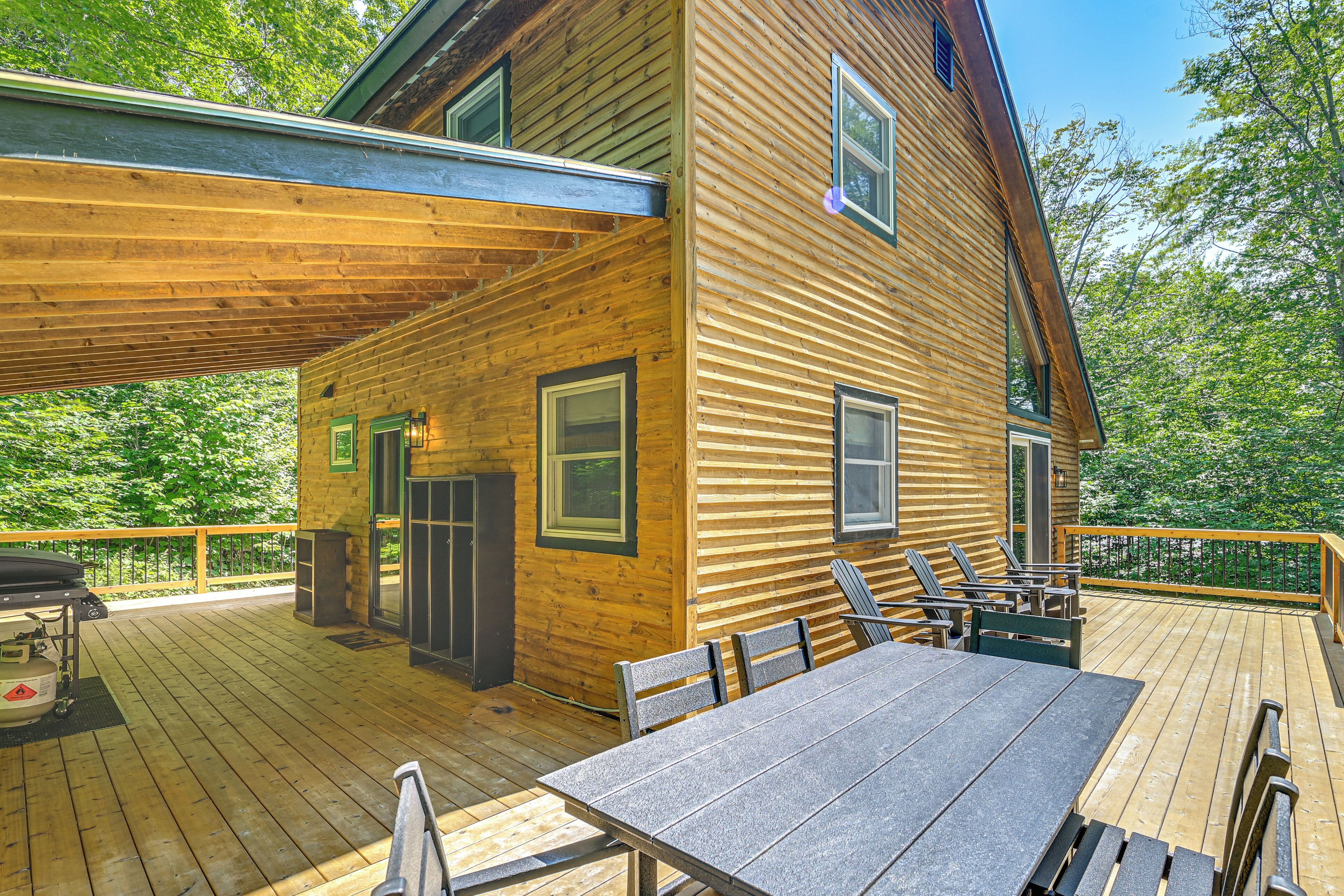 Une cabane en bois dotée d’une terrasse, d’un espace salon extérieur et d’un barbecue.