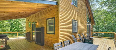 Une cabane en bois dotée d’une terrasse, d’un espace salon extérieur et d’un barbecue.