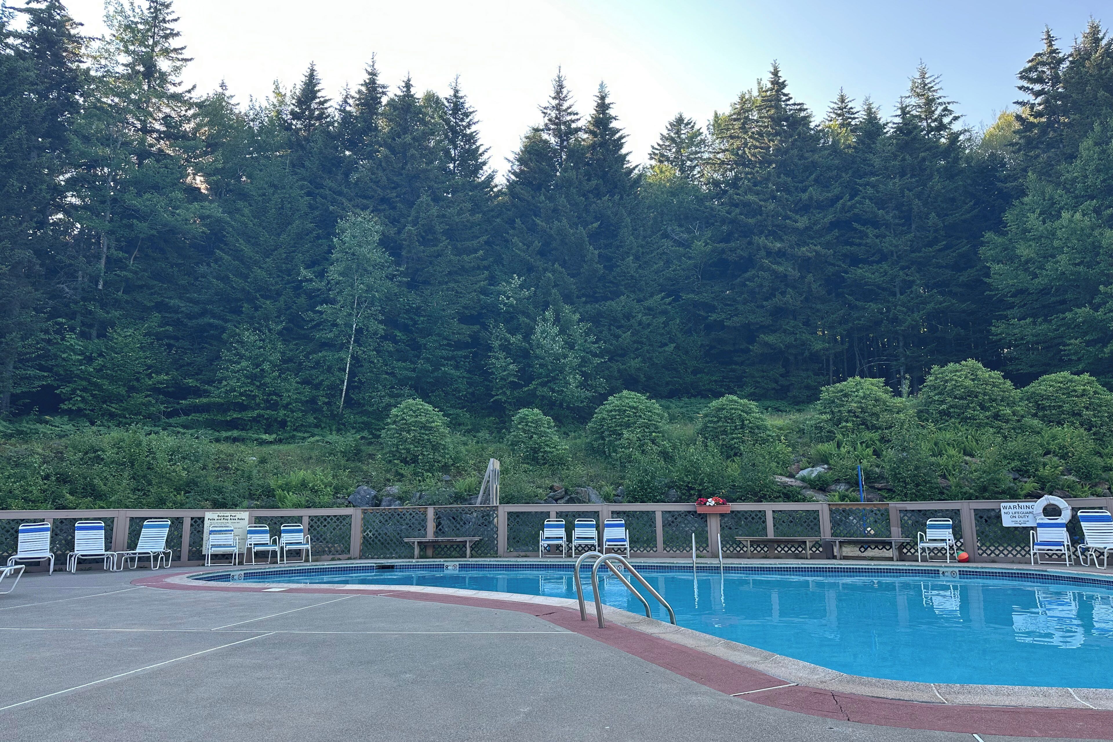 A swimming pool with lounge chairs and a wooden deck.