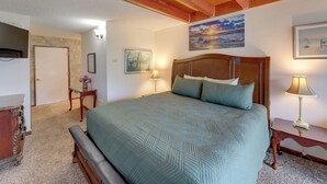 Ein Schlafzimmer mit einem großen Bett, Holzbalken an der Decke, einem Sonnenuntergangsbild und einer Lampe auf einem Nachttisch.