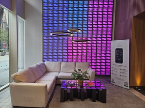 A modern hotel lobby with a sofa, a coffee table, and a decorative wall with a QR code.
