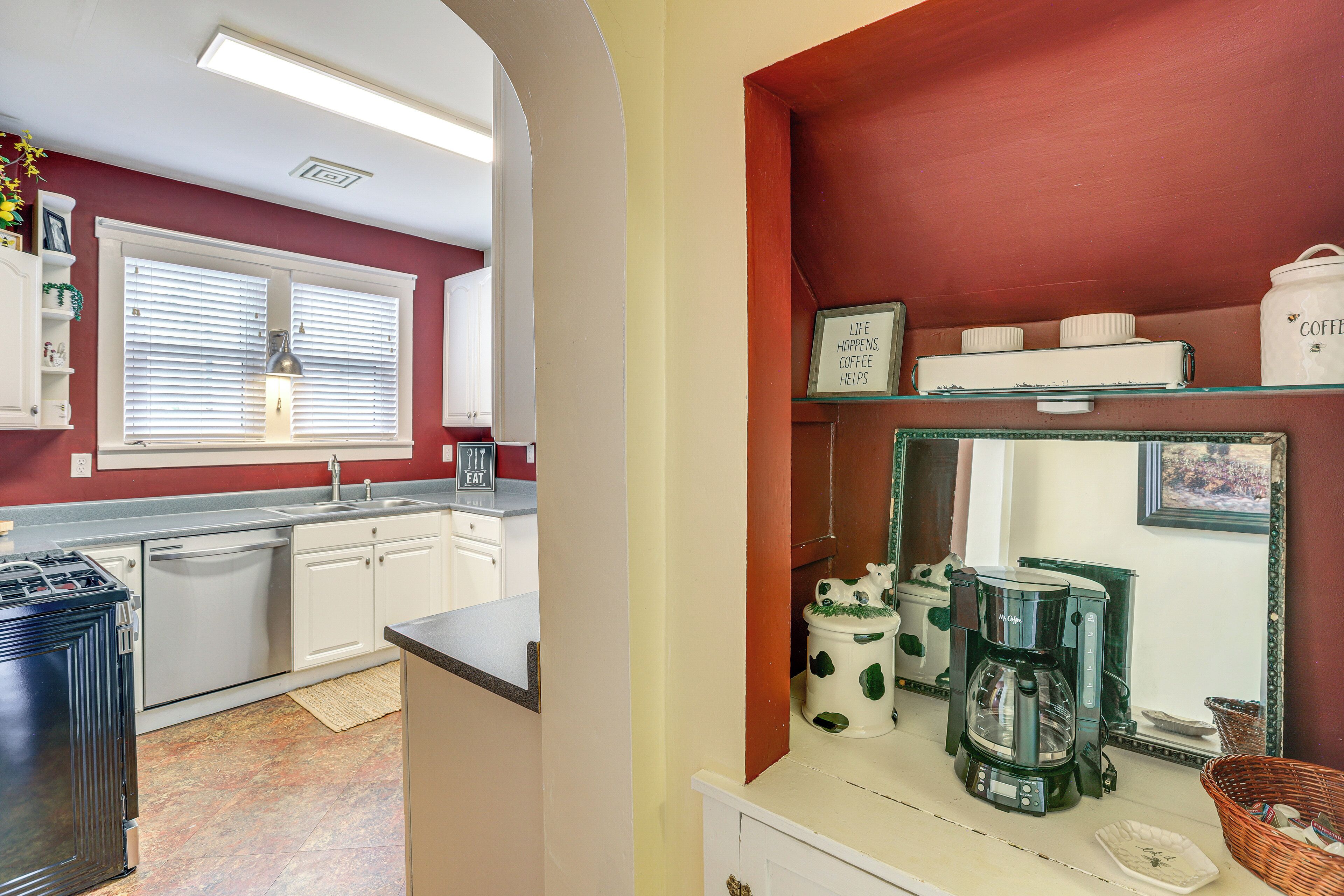 A kitchen with white cabinets, a coffee maker, and a framed sign on the wall.