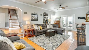A spacious living room with a gray sectional sofa, a coffee table, and a patterned rug. There is a staircase with a wooden railing leading to an upper floor. - Walk Everywhere! Dtwn Washmo Home Near Wineries (Washington)