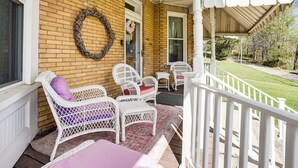 A porch with wicker furniture, a brick wall, and a covered area with a railing. - Groups Welcome! Historic Queen Anne Gem in Garrett (Garrett)