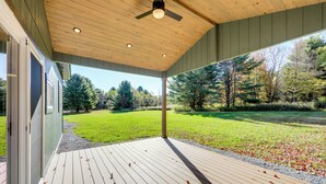 A wooden deck with a ceiling fan, a view of a grassy yard, and trees in the background. - Near All-season Trails! Modern Copenhagen Cabin (Copenhagen)