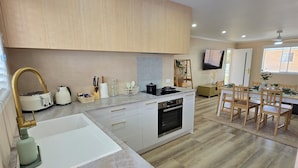 Eine moderne Küche mit Holzausstattung, einem eingebauten Backofen und einem Essbereich mit Tisch und Stühlen.