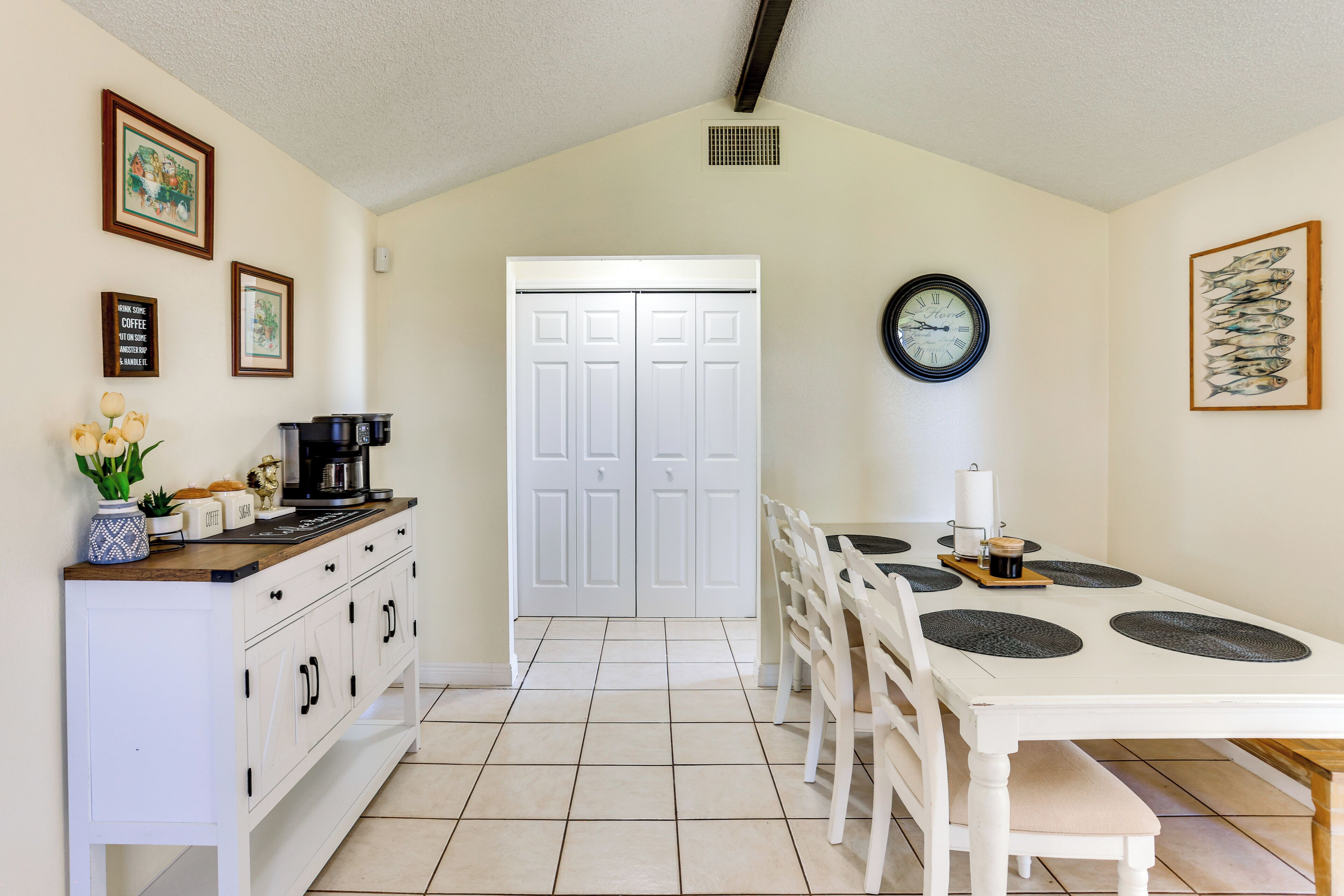 A kitchen with white cabinets, a coffee maker, and a dining table with placemats.