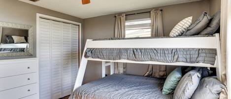 Dormitorio con literas, ventilador de techo, armario y ventana con cortinas.