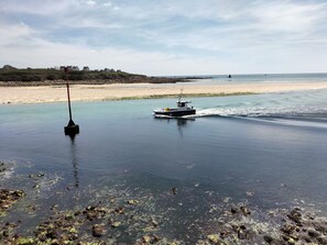 Una barca su acque calme nei pressi di una spiaggia sabbiosa, con un faro in lontananza.