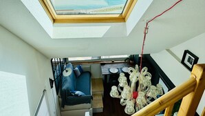 Een kamer met dakraam, een bank, een eettafel en een hanglamp.